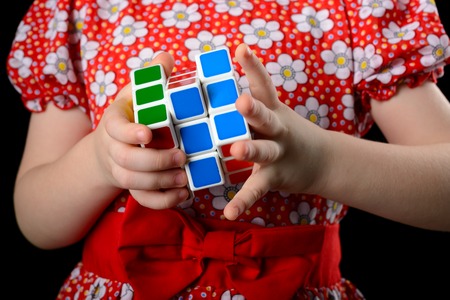 Almetyevsk City, Russia - February 7, 2017: a little girl holding a Rubik's cube on a black backgroundのeditorial素材