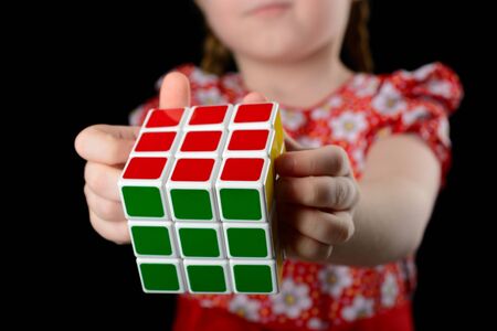 Almetyevsk City, Russia - February 7, 2017: a little girl holding a Rubik's cube on a black backgroundのeditorial素材
