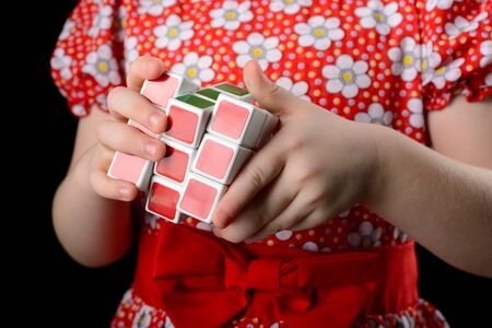 Almetyevsk City, Russia - February 7, 2017: a little girl holding a Rubik's cube on a black backgroundのeditorial素材