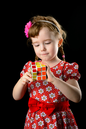 Almetyevsk City, Russia - February 7, 2017: a little girl holding a Rubik's cube on a black backgroundのeditorial素材