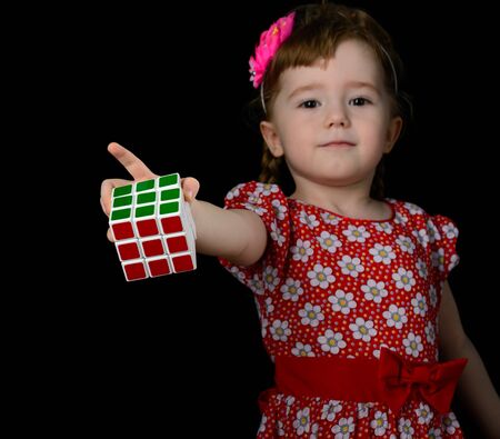 Almetyevsk City, Russia - February 7, 2017: a little girl holding a Rubik's cube on a black backgroundのeditorial素材