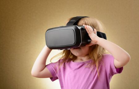 Little girl playing in virtual goggles indoorsの写真素材