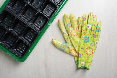 Plastic containers for seedlings and gloves on a wooden tableの写真素材