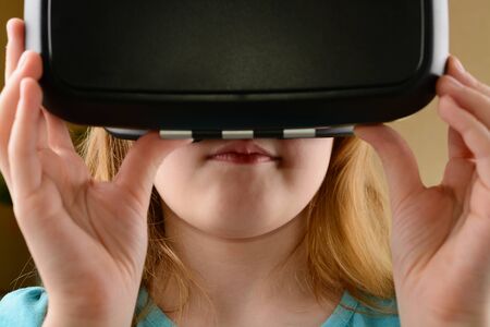 Little girl playing in virtual goggles indoorsの写真素材