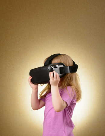 Little girl playing in virtual goggles indoorsの写真素材