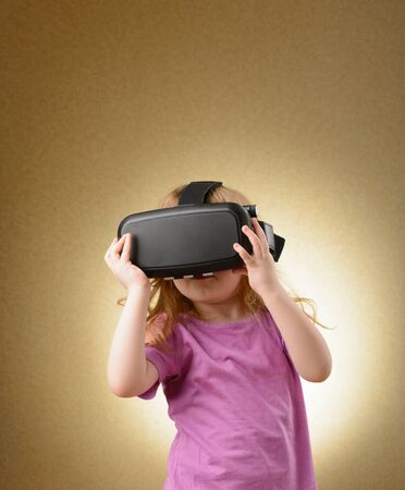 Little girl playing in virtual goggles indoorsの写真素材