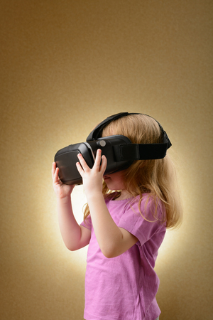 Little girl playing in virtual goggles indoorsの写真素材