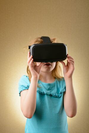 Little girl playing in virtual goggles indoorsの写真素材