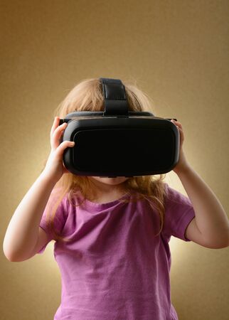 Little girl playing in virtual goggles indoorsの写真素材