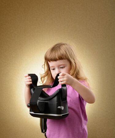 Little girl playing in virtual goggles indoorsの写真素材
