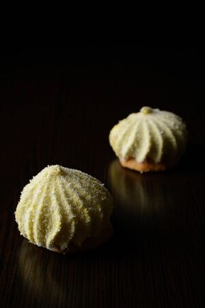 Two cakes sprinkled with coconut chips on a dark wooden tableの写真素材