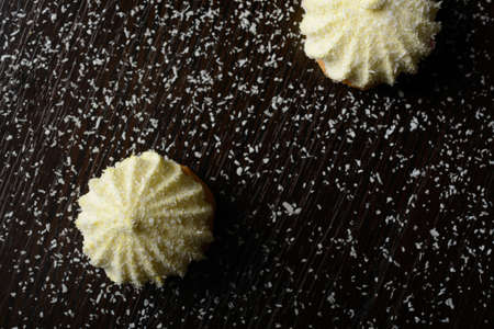 Two cakes sprinkled with coconut chips on a dark wooden tableの写真素材