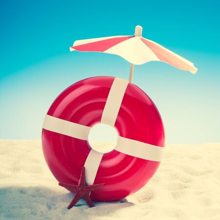 Umbrella and swimming ring at the beach on background of blue skyの写真素材