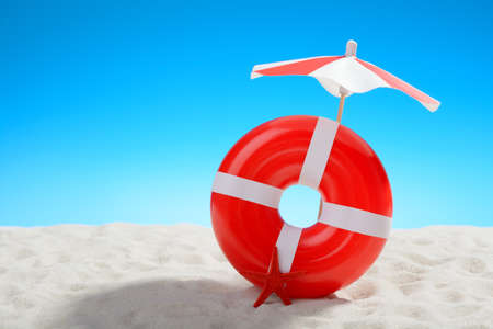 Umbrella and swimming ring at the beach on background of blue skyの写真素材