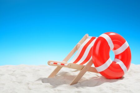 Deckchair and swimming ring on the beach on background of blue skyの写真素材