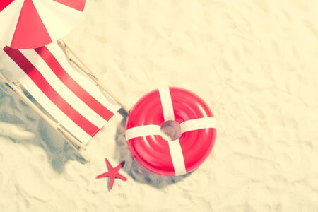 Red and white deckchair and swimming ring on the beach: top viewの写真素材