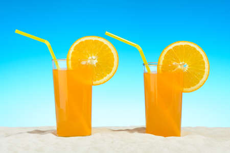Two glasses of orange juice on the beachの写真素材