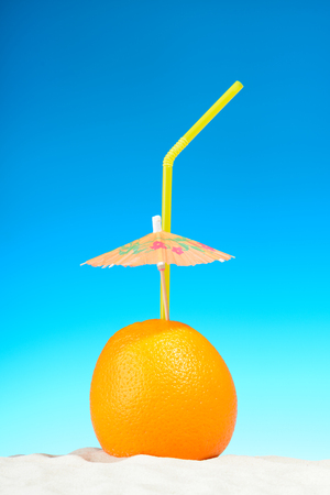 Orange with straw on the beachの写真素材