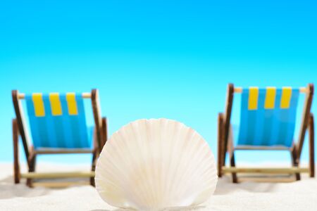 Seashell and two sunbeds at the beach on background of blue skyの写真素材