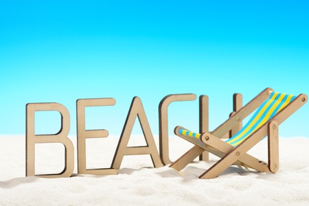 The word BEACH and sunbed at the beach on background of blue skyの写真素材