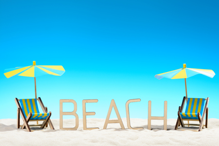 The word BEACH and two sunbeds at the beach on background of blue skyの写真素材