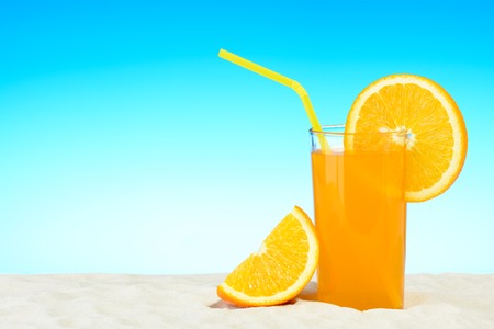 A glass of orange juice on the beachの写真素材