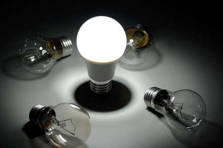 Glowing led lamp and incandescent bulbs in the darkの写真素材