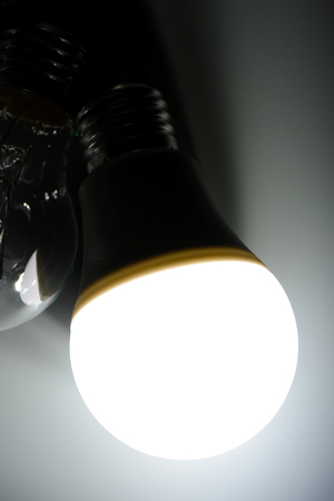 Glowing led lamp and incandescent bulb in the darkの写真素材