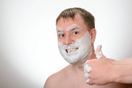A man smeared with shaving foam shows likeの写真素材