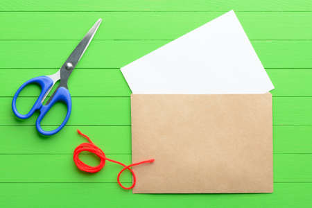 A blank piece of paper with an envelope on green wooden backgroundの写真素材