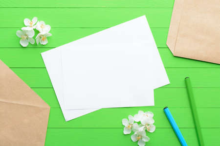 A blank piece of paper with an envelope on green wooden backgroundの写真素材