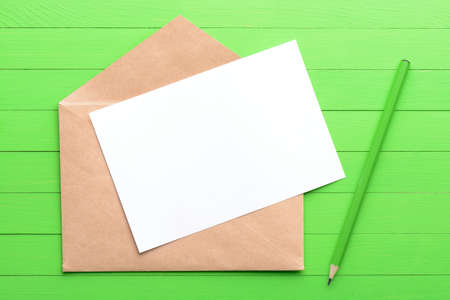 A blank piece of paper with an envelope on green wooden backgroundの写真素材