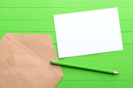 A blank piece of paper with an envelope on green wooden backgroundの写真素材