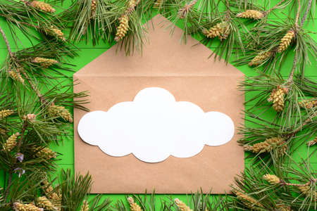 A blank piece of paper with an envelope among pine branches on a green wooden backgroundの写真素材