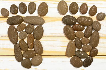 Top view of footsteps made with stones and arranged on wooden surface.の写真素材