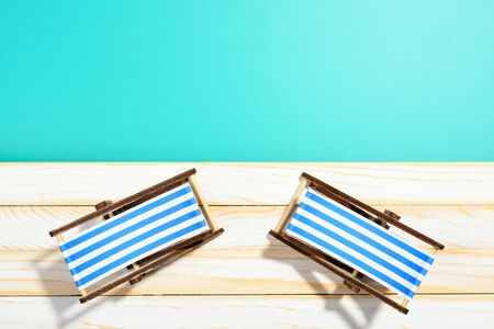 Two striped beach chairs on wooden surface and blue backgroundの写真素材