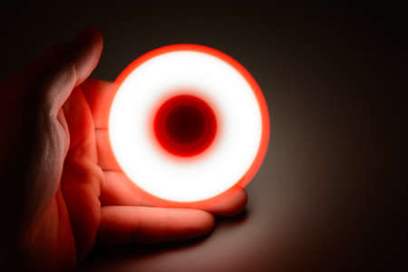 From above shot of crop hand holding spinning fidget in the dark