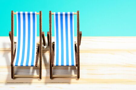Two striped beach chairs on wooden surface and blue backgroundの写真素材