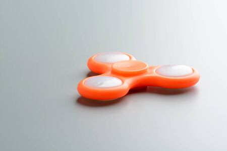 Close-up shot of orange fidget spinner on gray surface.の写真素材