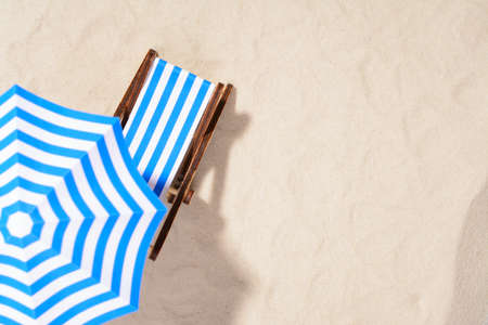 From above of lounge area on beach with striped chair under umbrella.