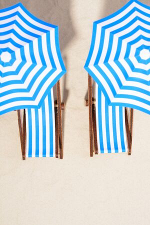From above shot of striped chairs under umbrellas on beach.の写真素材