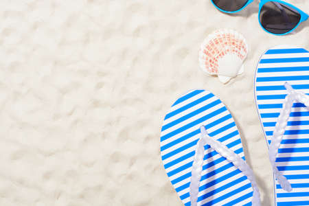 From above shot of striped flip flops on sand with sunglassesの写真素材