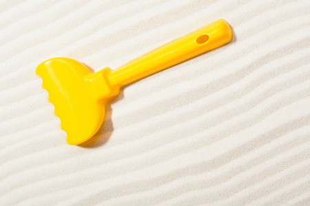 From above shot of yellow plastic rake for sandbox and drawing on sand.の写真素材