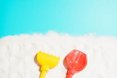 Closeup of red shovel and yellow rake on sandの写真素材