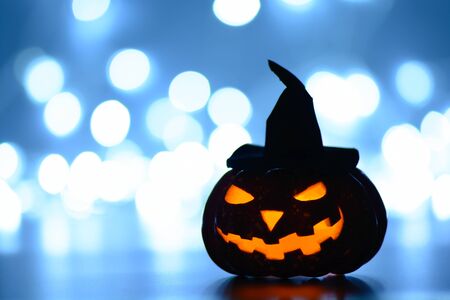 Illuminated pumpkin lantern in hat for Halloween celebration on bokeh?backgroundの写真素材