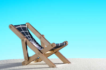 Studio shot of small lounge chair with web on textile placed on sand