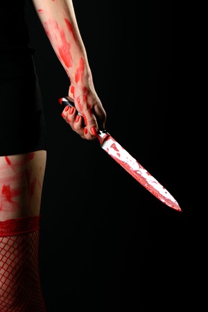 Mid section of woman wearing red stockings holding bloody knifeの写真素材