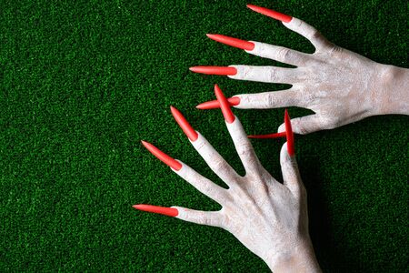 Horrifying sharp vampire claw hands on fake green turf with copy space in a halloween horror theme.の写真素材