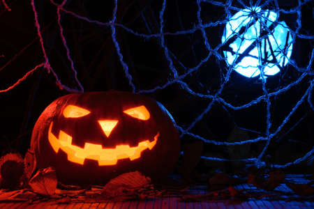 Horrible Halloween pumpkin in the background of the web and the full moonの写真素材