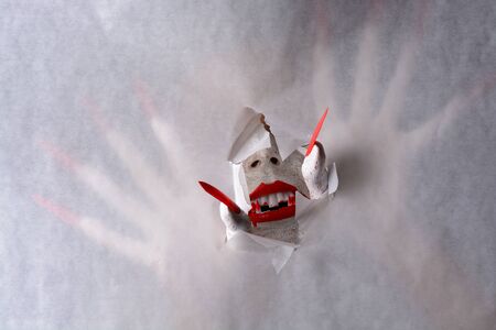 A horrifying vampire tearing a hole through paper with sharp red claws revealing blood dripping fangs in a halloween horror theme.の写真素材